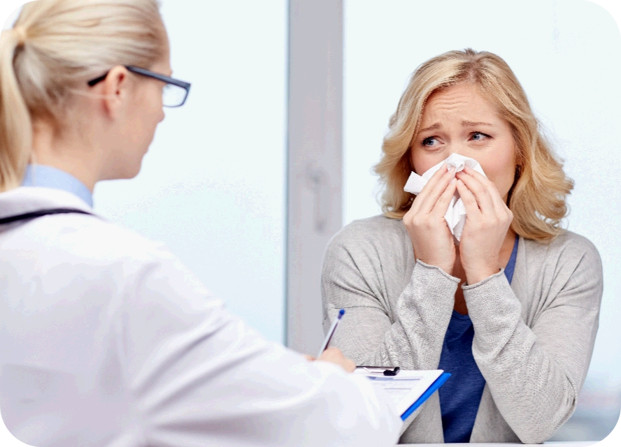 Ärztin berät eine niesende Patientin zur Behandlung der allergischen Rhinitis